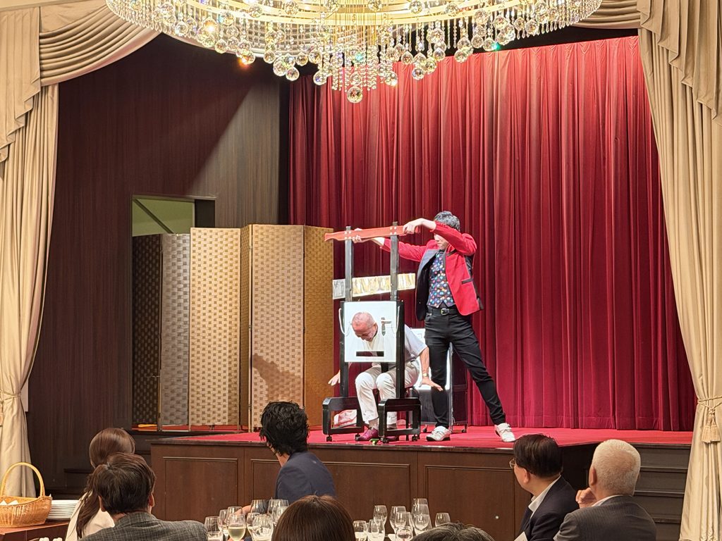 旧桜ノ宮公会堂のステージでギロチンイリュージョンを披露するマジシャンMASA